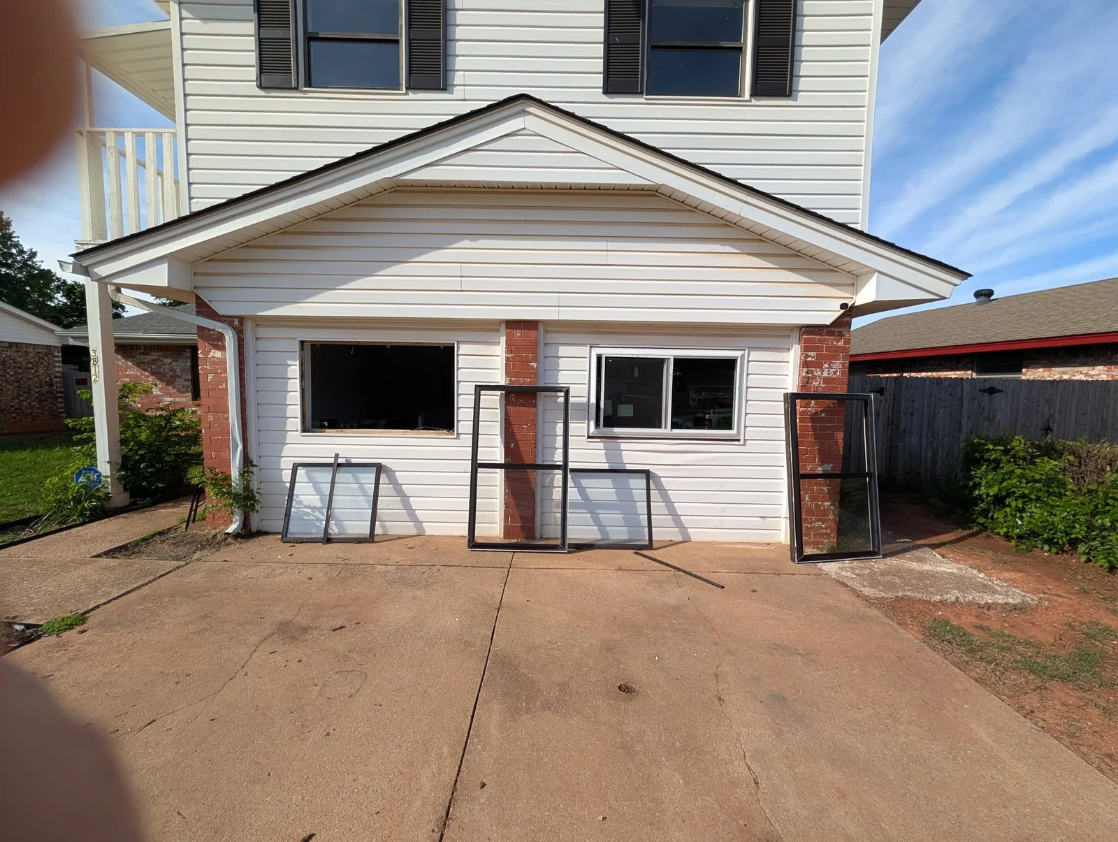 New double-hung windows with black frames installed on white vinyl siding home facade