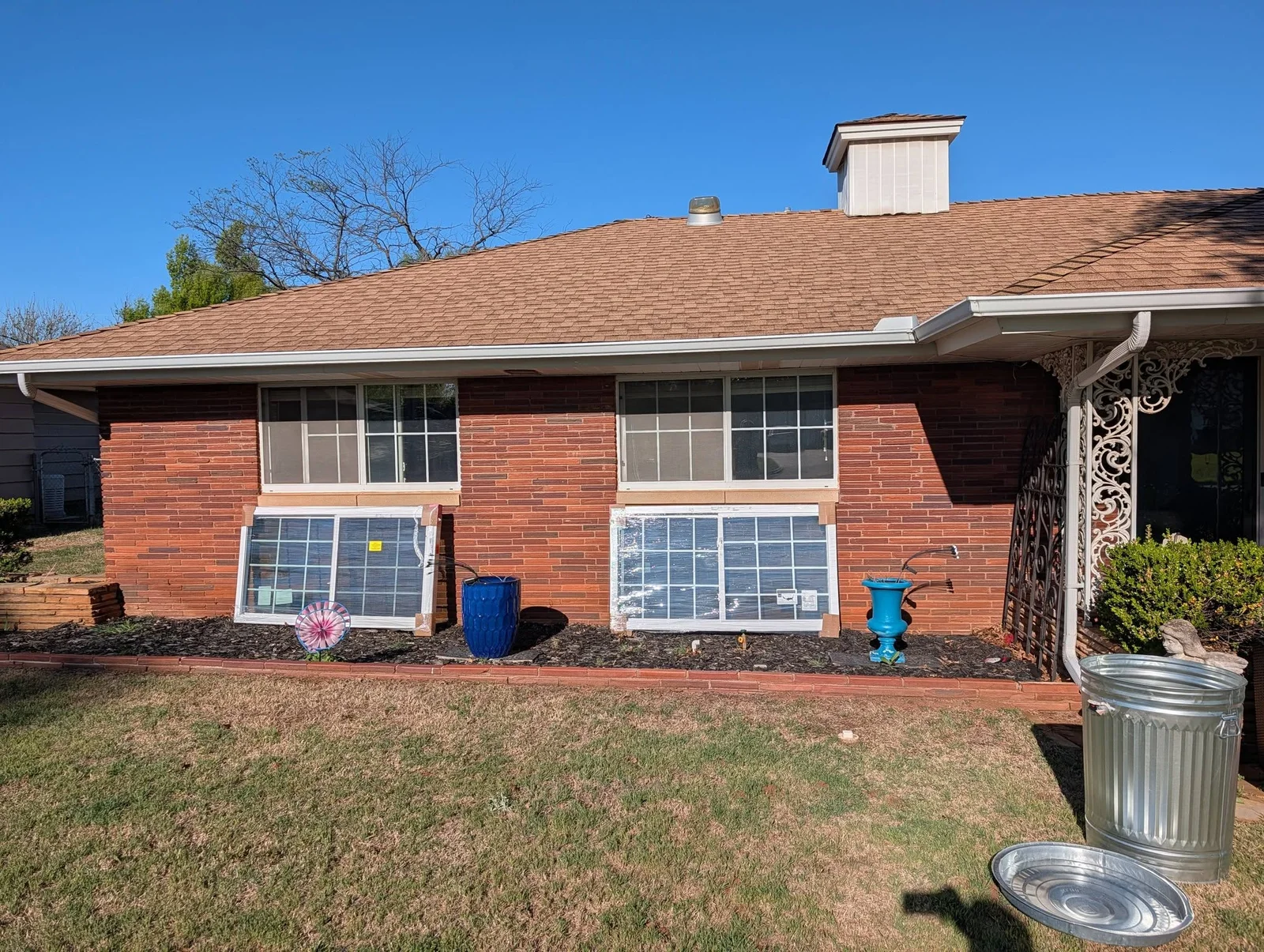 New white double-hung windows installed on red brick residential home facade