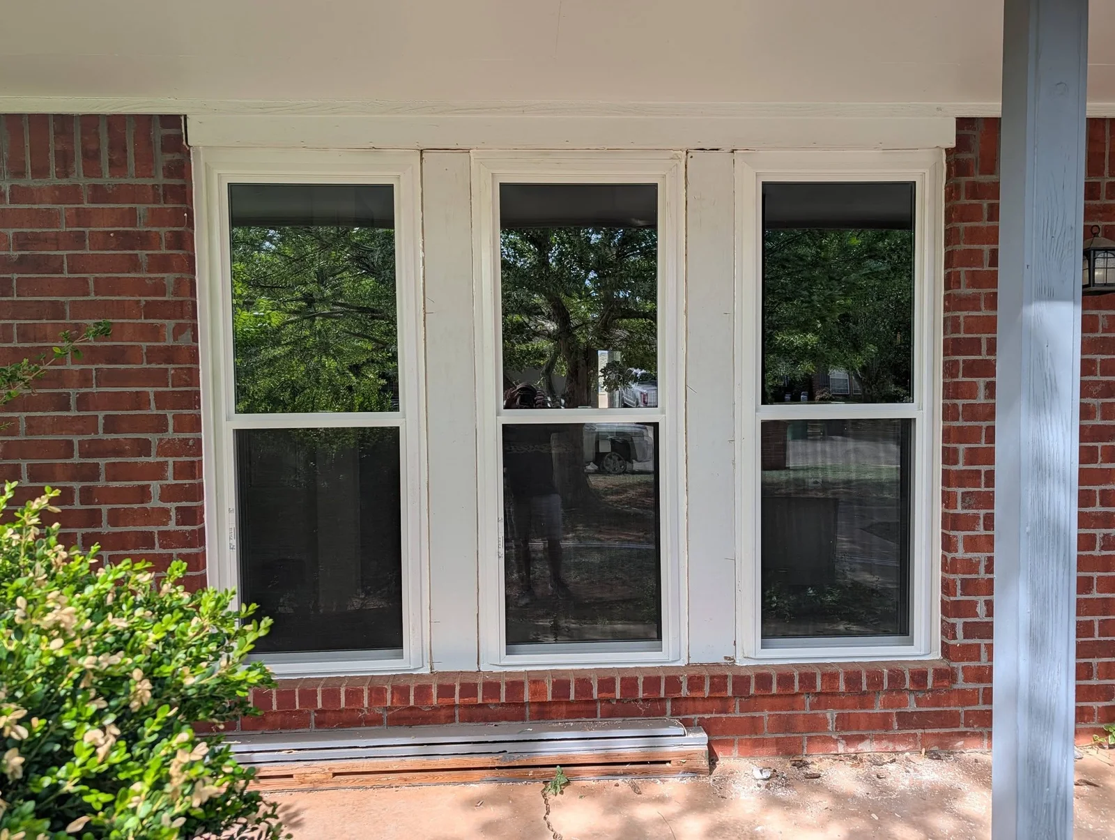 Three white-framed double-hung windows with black sashes installed on red brick wall