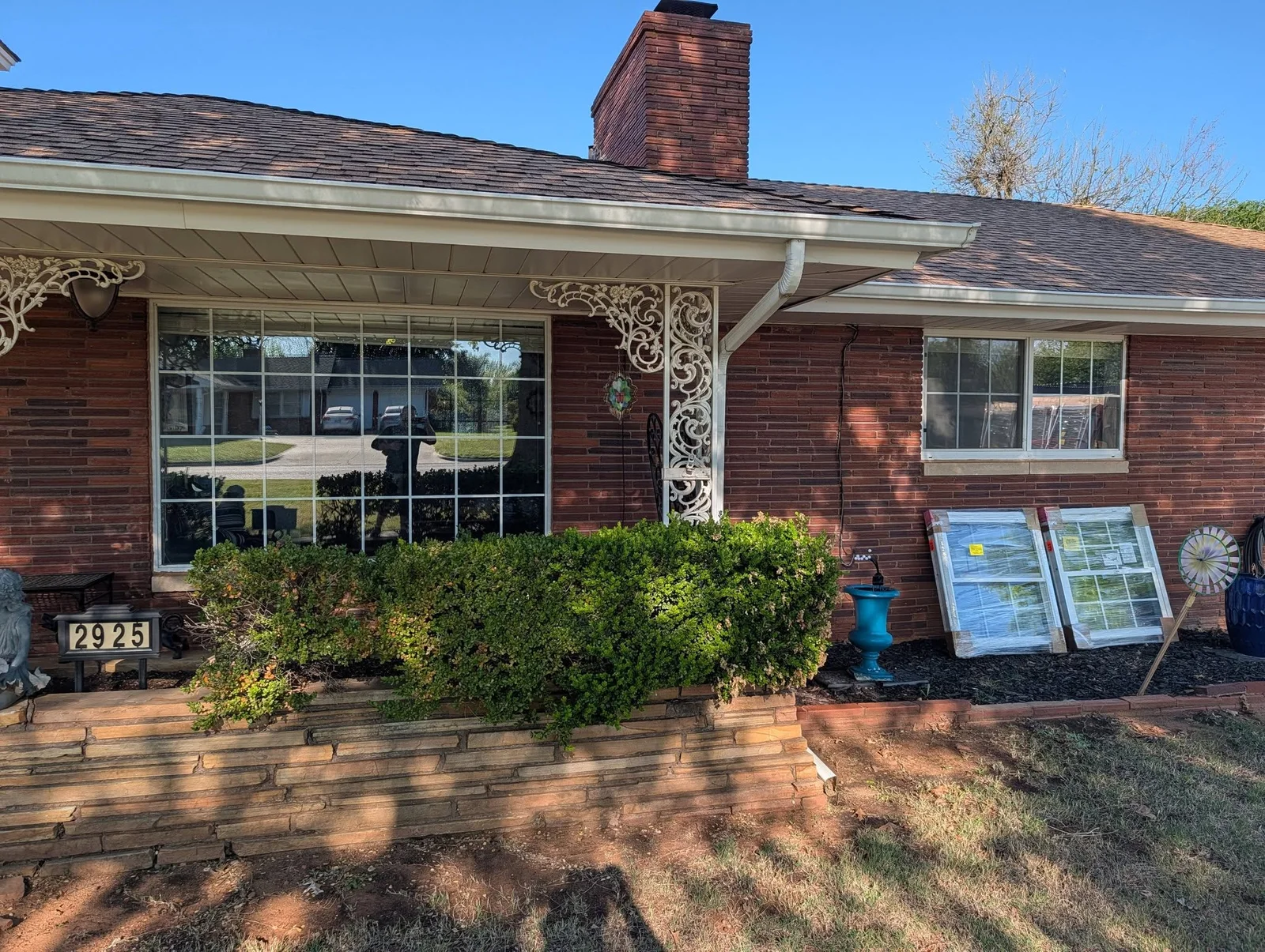 Large picture windows installed on red brick home with white trim and decorative corbels