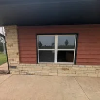 Black double-hung windows installed on brick and red siding home exterior
