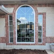 Large arched multi-pane window with brick surround on residential entry