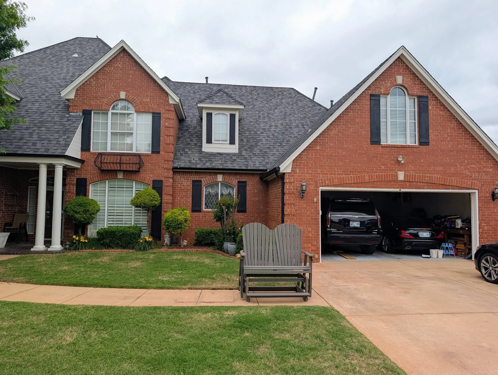 Brick home with newly installed replacement windows, black shutters, and white interior shutters on front facade