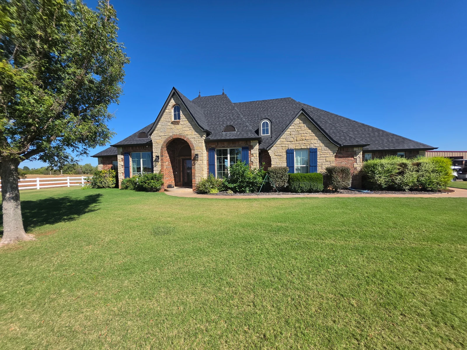 Stone and brick home with custom arched and casement windows, blue trim, gabled roof